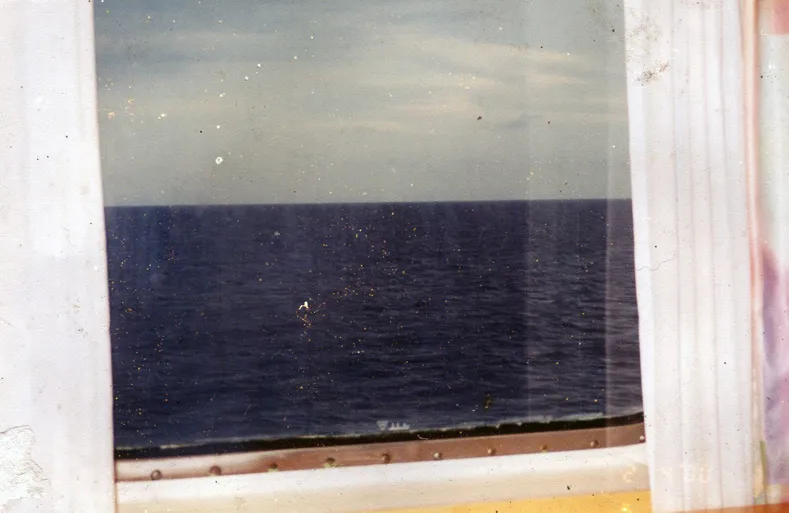 A found photograph of a view over water towards the horizon as seen through a ship's window